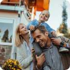 A young family walk together outside their home.